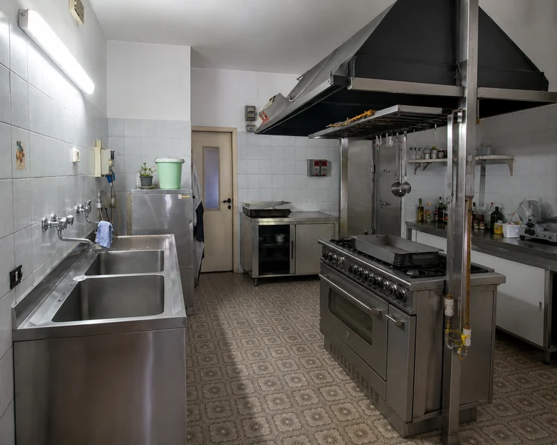 La cucina professionale separata, con fornelli, cappa e piani in acciaio
