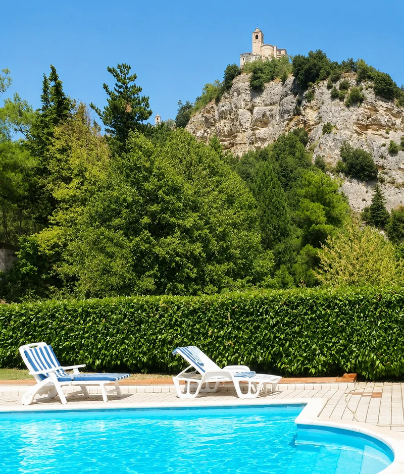 La piscina con il borgo di Montefalcone Appennino sulla rupe, tra gli alberi