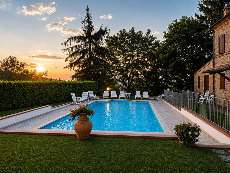 La piscina privata al tramonto, con lettini, alberi e la villa sulla destra