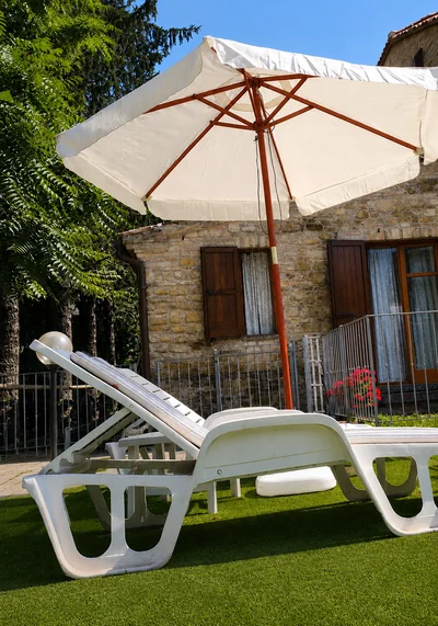 Lettini e ombrellone sul prato accanto alla villa