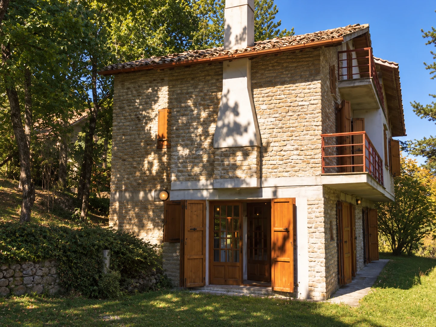 La facciata di Casa dello Scoiattolo, circondata dagli alberi a Montefalcone Appennino