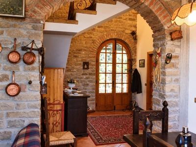 Ingresso con pareti in pietra, porta di legno ad arco e tappeto
